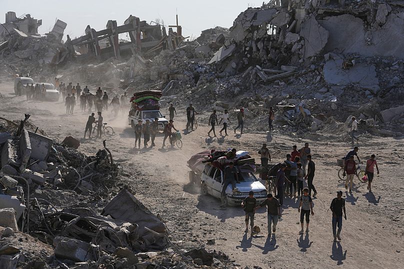 Des Palestiniens déplacés passent devant des bâtiments détruits alors qu'ils regagnent leurs maisons dans le quartier de Zeitoun, à Gaza, le 10 octobre 2025