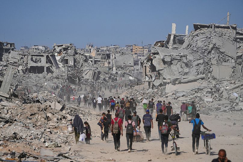 Displaced Palestinians pass by destroyed buildings as they return to their homes in the Zeitoun neighbourhood of Gaza City, 10 October, 2025