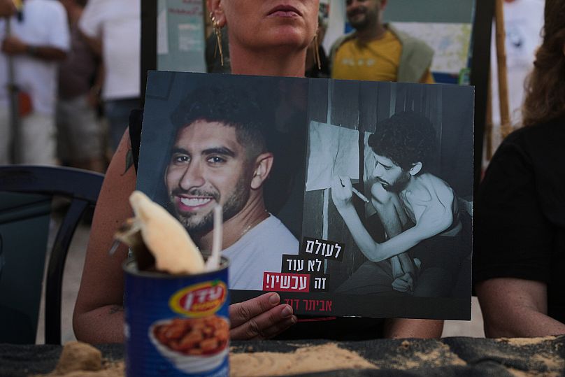 A woman holds a photo of Israeli hostage Evyatar David, showing him before and during his captivity in the Gaza Strip, in Tel Aviv, Israel, Saturday, Aug. 9, 2025. 