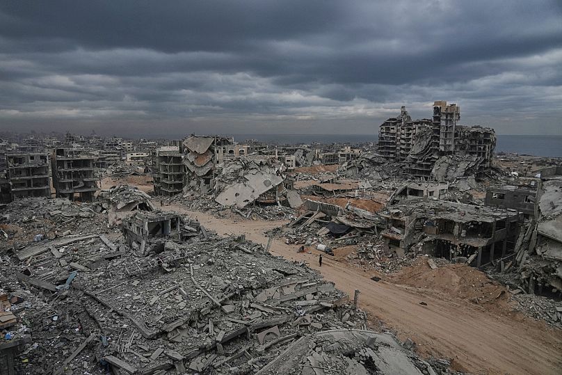 Displaced Palestinians walk amid destroyed buildings in the Shati refugee camp in Gaza City, Sunday, Oct. 12, 2025.