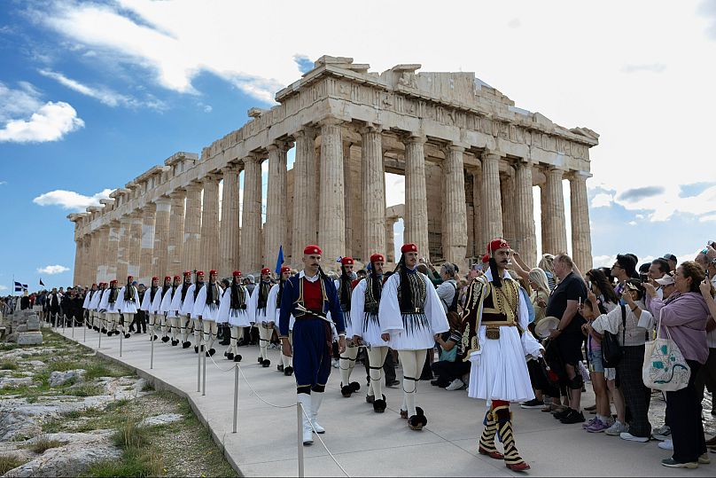 Presidential Guards walk past the free of scaffolding Parthenon temple on the Acropolis hill in Athens, Sunday, Oct. 12, 2025