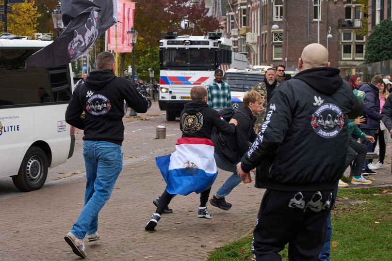 Des manifestants anti-immigration agressent un homme, au centre droit, lors d'une manifestation à Amsterdam, aux Pays-Bas, le dimanche 12 octobre 2025.