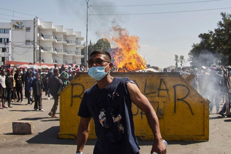 An protester watches police near burning barricades during a protest calling for the president to step down in Antananarivo, Madagascar, Thursday, Oct. 9, 2025.