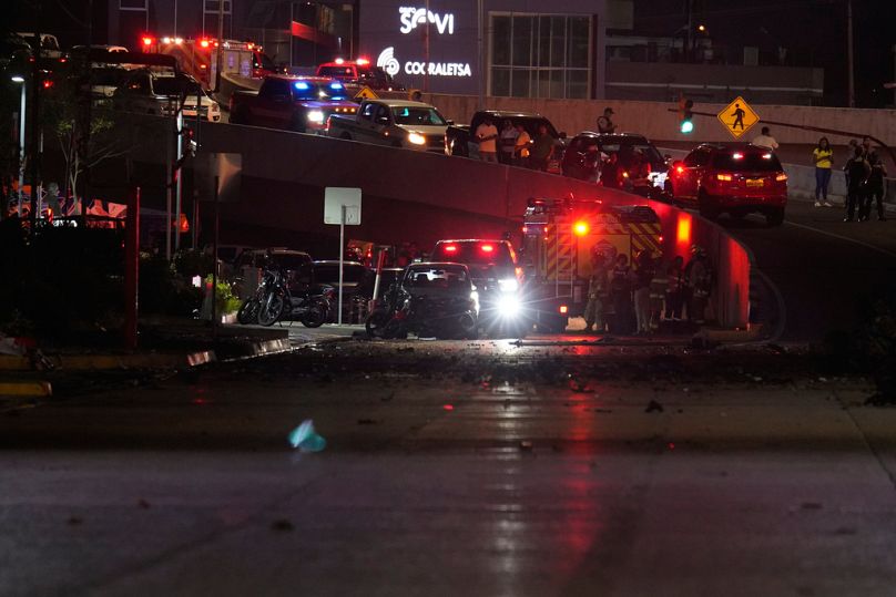 Policías, bomberos y agentes inspeccionan los daños en el lugar donde se produjo la explosión de un coche en una calle de Guayaquil, Ecuador, el 14 de octubre de 2025.