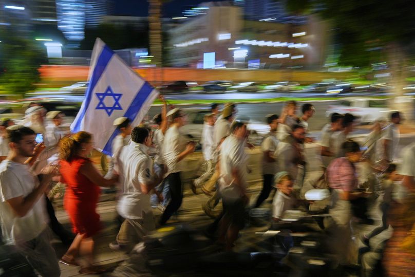 Zsidó ünneplők táncolnak és tartják a Tórát, miközben a Szimchát Tóra ünnepét ünneplik a Túszok tereként ismert tér mellett, Tel-Avivban, Izraelben, 2025. október 14-én.