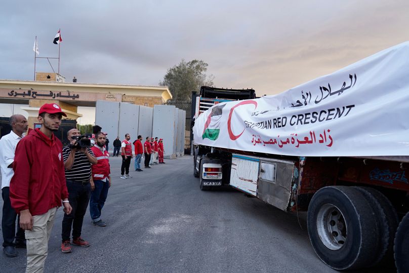 Membros do Crescente Vermelho egípcio vigiam os camiões que transportam ajuda humanitária à medida que entram na passagem de Rafah entre o Egito e Gaza, 12 de outubro de 2025