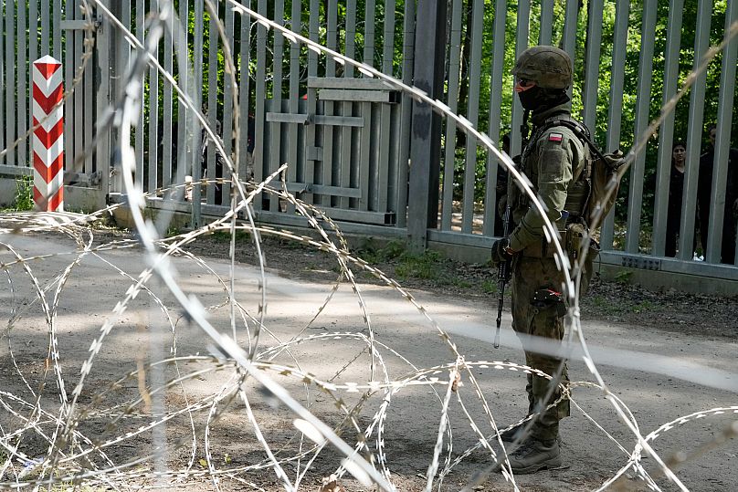 A soldier stands guard by a metal barrier in Bialowieza Forest in eastern Poland, 29 May, 2024