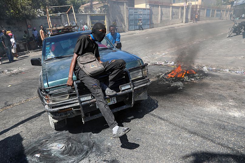 A protester sits on the bonnet of a car during a demonstration to demand government action against gang violence in Port-au-Prince, 20 February, 2025