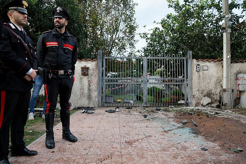 Parts of a car are seen on the ground as Carabinieri military police stand outside the home of investigative journalist Sigfrido Ranucci in Pomezia, 17 October, 2025