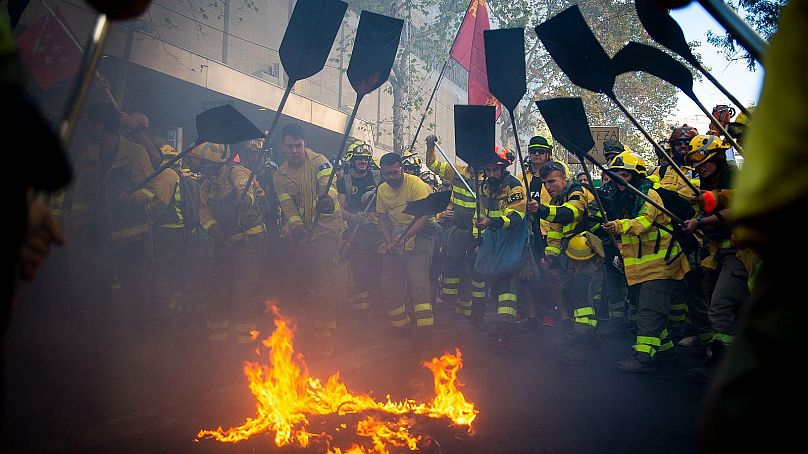 Bomberos forestales apagando un fuego como protesta, durante la manifestación del 18 de octubre de 2025
