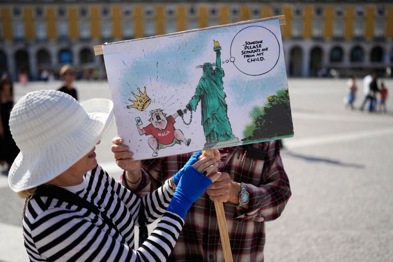 Um casal prepara um cartaz antes de se juntar a um protesto contra os reis organizado por cidadãos norte-americanos residentes em Portugal, no centro de Lisboa.