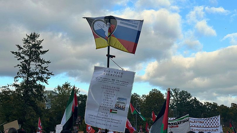 Eine deutsch-russische Flagge und ein Schild auf einer pro-Palästina Demo in Berlin