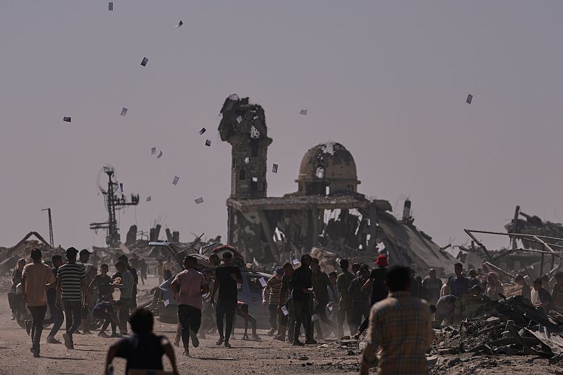 Varios palestinos recogen octavillas lanzadas por un dron israelí en las que se advierte a la población de que se mantenga alejada de la denominada línea amarilla en Jan Yunis