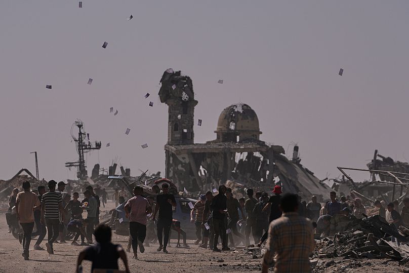 Des Palestiniens ramassent des tracts largués par un drone israélien avertissant la population de rester à l'écart de la "ligne jaune" à Khan Younès, le lundi 20 octobre 2025