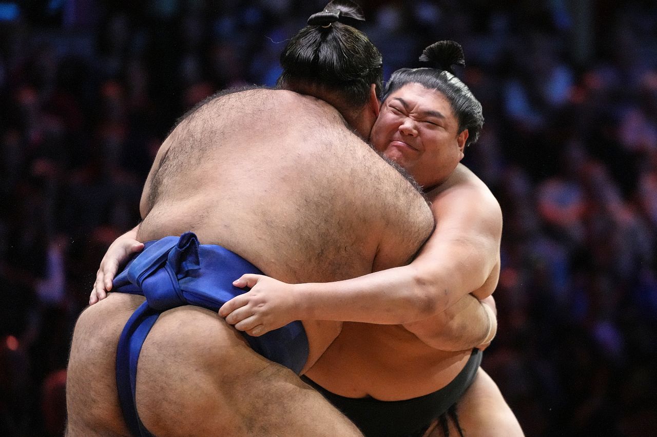 Sumo wrestlers, Takayasu, rear, and Abi push during their bout on the dohyo. 