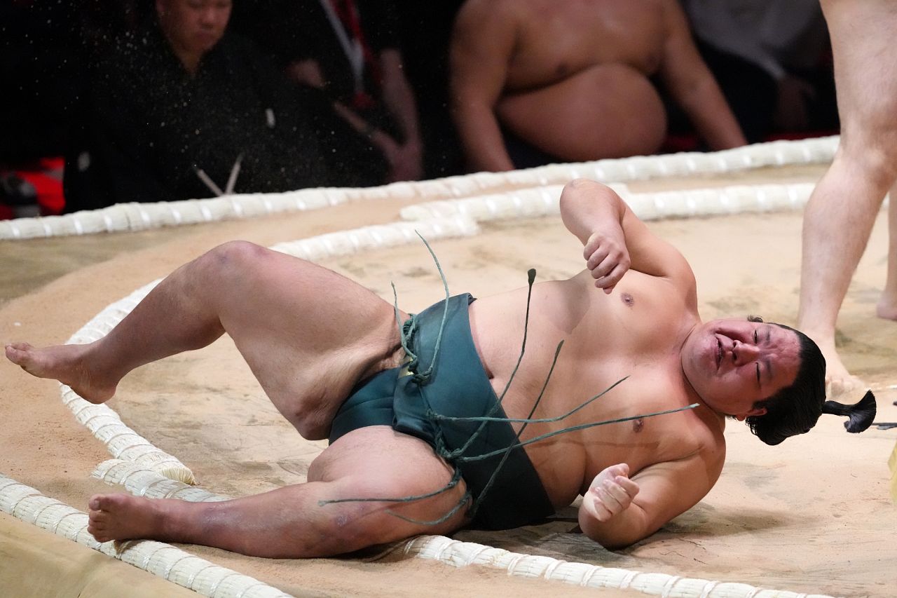 A Sumo wrestler lands on the edge of the ring during The Grand Sumo Tournament. 