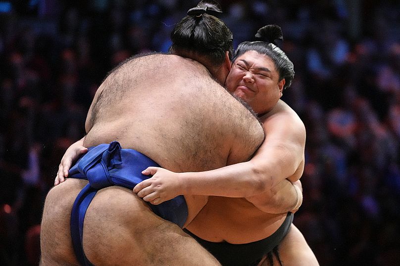 Los luchadores de sumo Takayasu, por detrás, y Abi empujan durante su combate en el dohyō. 