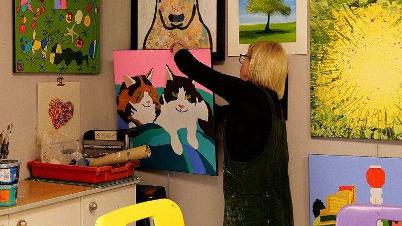 Sandra Hampton hanging artwork on the wall
