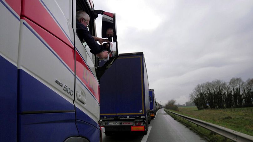 Un chauffeur de camion britannique nettoie un rétroviseur alors qu'il fait la queue sur l'autoroute A16 pour embarquer sur un ferry afin de rejoindre l'Angleterre, près de Calais, dans le nord de la France, le 9 décembre 2020.