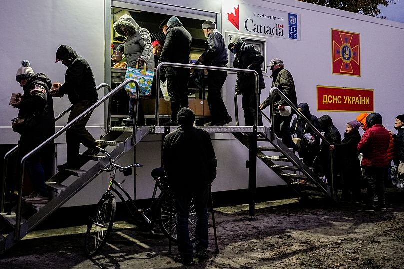 Des personnes reçoivent des repas gratuits à un point de distribution lors d'une coupure d'électricité à Shostka, le 16 octobre 2025.