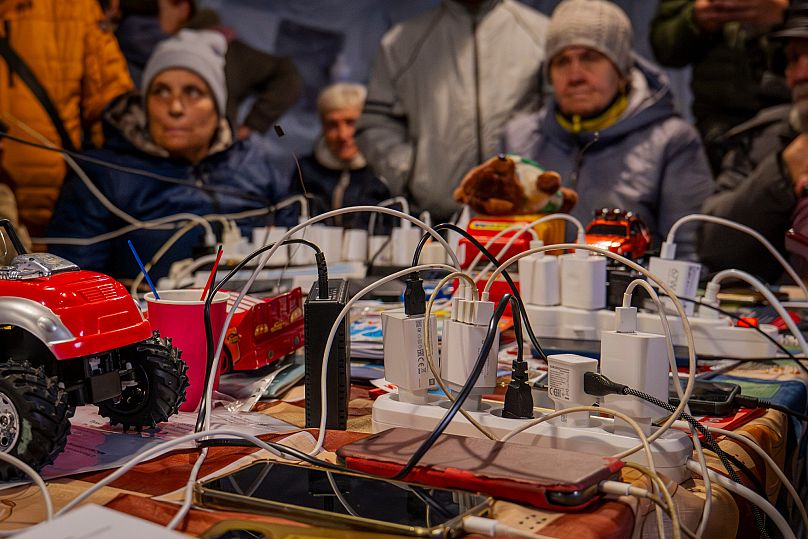 Des personnes chargent leur téléphone dans l'une des tentes chauffées mise à disposition. 
