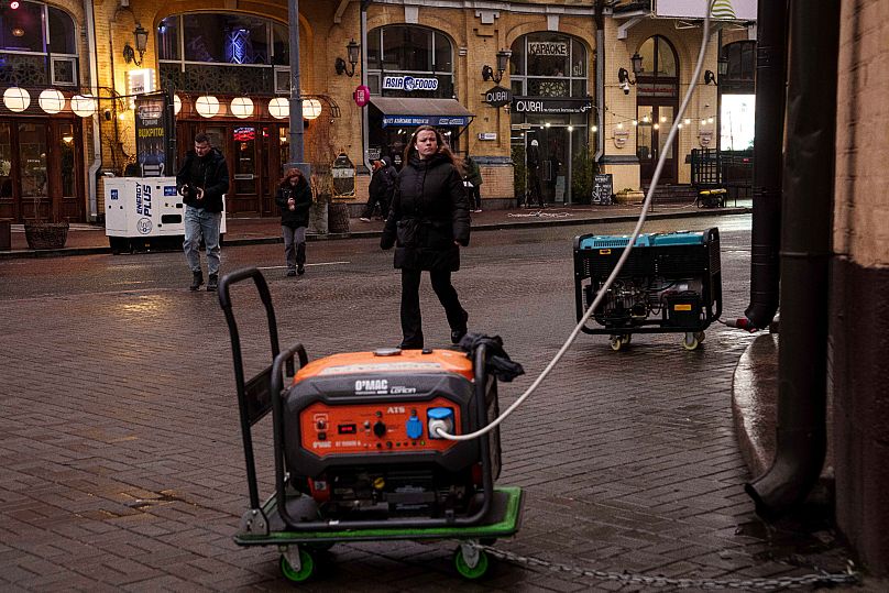 Des personnes marchent dans une rue où de nombreuses entreprises sont alimentées par des générateurs pendant une panne d'électricité à Kiev, le 29 novembre 2024.