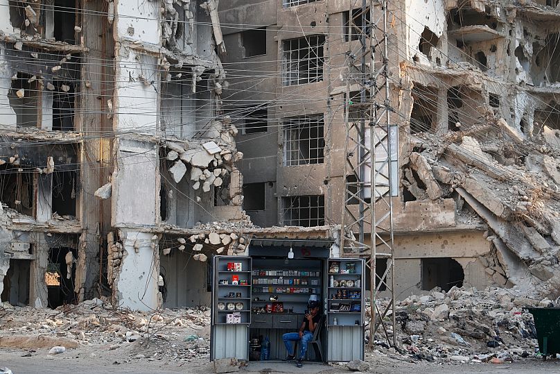 A man sits in front of war-damaged buildings in the Damascus suburb of Daraya, 4 October, 2025