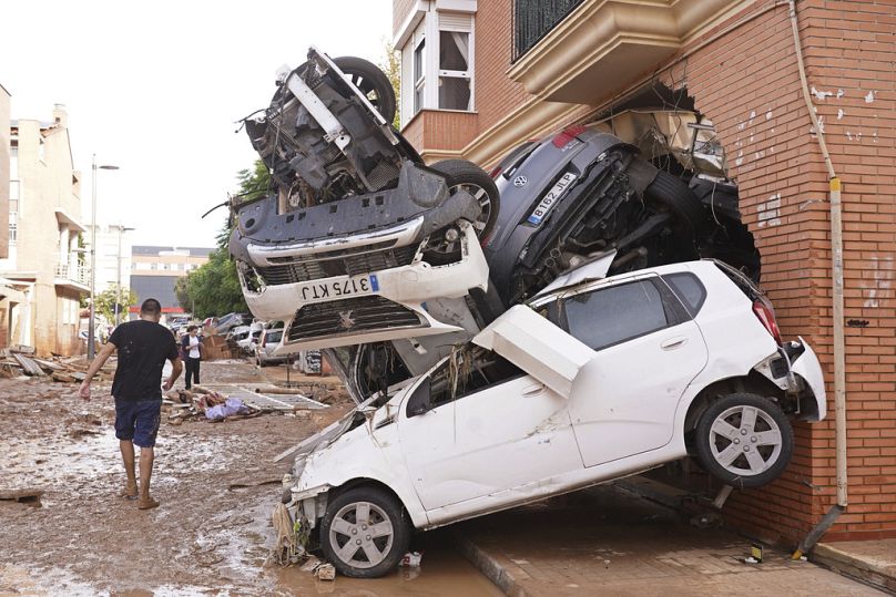 Un hombre camina junto a una pila de coches tras las inundaciones en Massanassa, a las afueras de Valencia, España, el viernes 1 de noviembre de 2024.