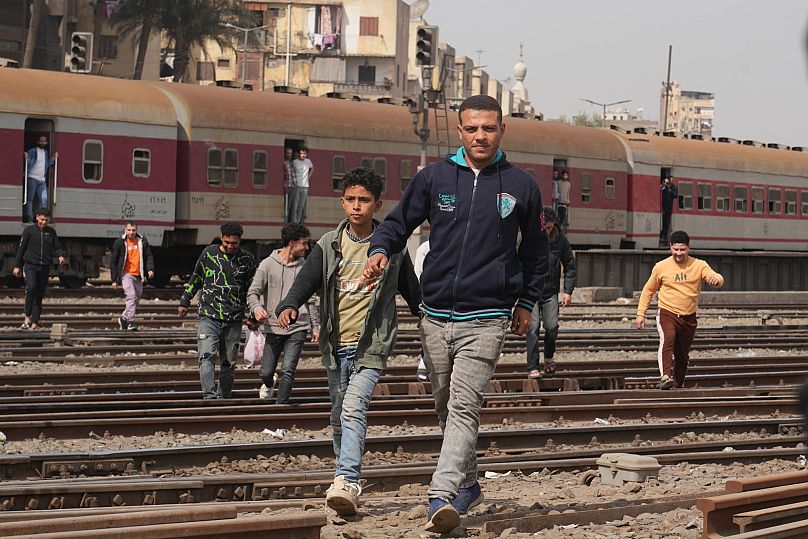 Egyptian passengers cross the railway at a popular district in Cairo, 13 March, 2025
