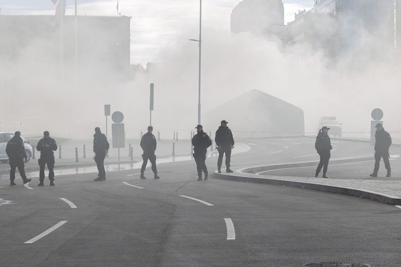 Police officers stand on a street as a fire is localized inside the government supporters' camp outside the Serbian parliament in Belgrade, Serbia, Wednesday, Oct. 22, 2025