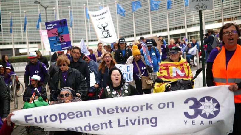 FILE: People gather outside the European Commission headquarters in Brussels, Wednesday, Oct. 2, 2019, demanding better independent living support for disabled people. 