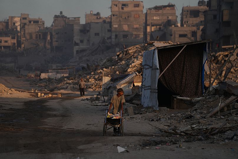 Palestinians walk trough the destruction caused by the Israeli air and ground offensive in in Gaza City, 22 October, 2025