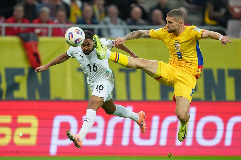 A román Daniel Birligea (sárgában) és az osztrák Philipp Mwene harcol a labdáért  a Románia-Ausztria vb-selejtezőn Bukarestben, 2025. október 12-én