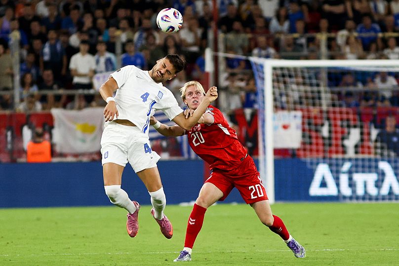 A görög Konsztantínosz Mavropánosz (fehérben) és a dán Mika Biereth a Görögország-Dánia (0-3) világbajnoki selejtező mérkőzésen Pireuszban 2025. szeptember 8-án