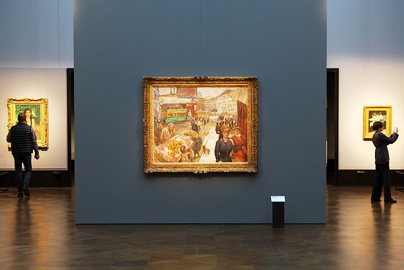 Gazeteciler Pierre Bonnard'ın 1867-1947 yılları arasında yaptığı "Place Clichy" tablosunun yanında yürüyor.