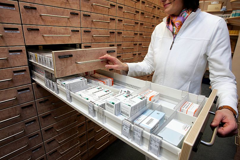 Apothekerin zeigt Medikamente im Regal