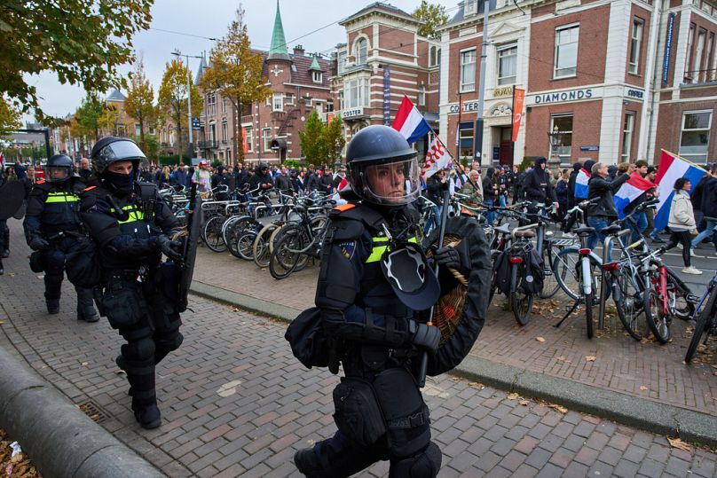 Dutch riot police escort anti-immigration protesters during a demonstration in Amsterdam, Netherlands, 12 October 2025