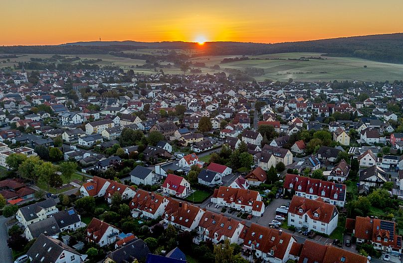The sun rises on the horizon above houses in Wehrheim near Frankfurt, 8 September, 2023