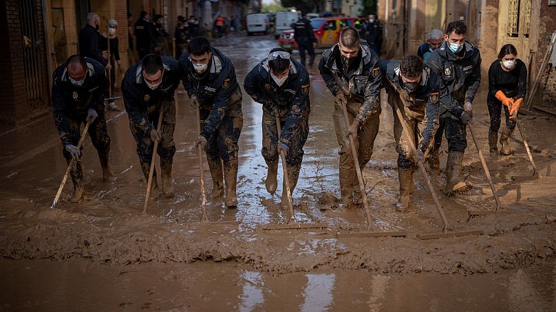 Miembros de la Policía Nacional española retiran el barro de una calle afectada por las inundaciones en Masanasa, Valencia, España, el miércoles 6 de noviembre de 2024.