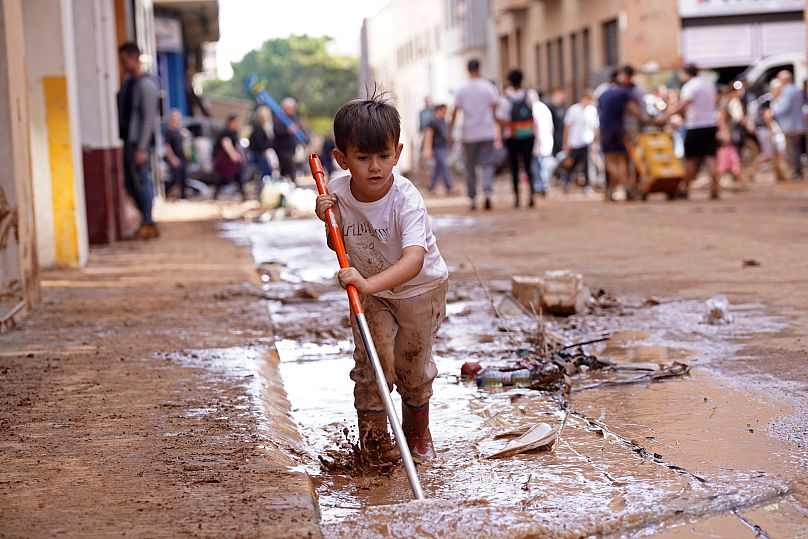 Un niño ayuda a retirar el lodo de una calle tras las inundaciones en Massanassa, a las afueras de Valencia, España, el viernes 1 de noviembre de 2024.