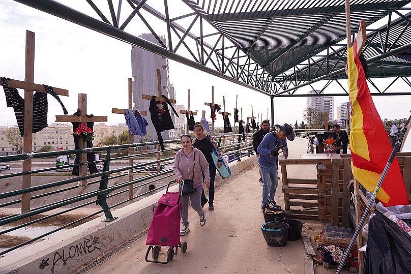 People pass by symbolic crosses on a bridge after floods in Catarroja that left hundreds dead or missing in Valencia, 12 November, 2024