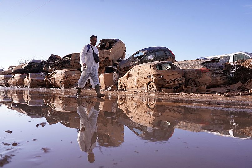A man walks past stacked up cars after floods in Catarroja that left hundreds dead or missing in the Valencia region, 12 November, 2024