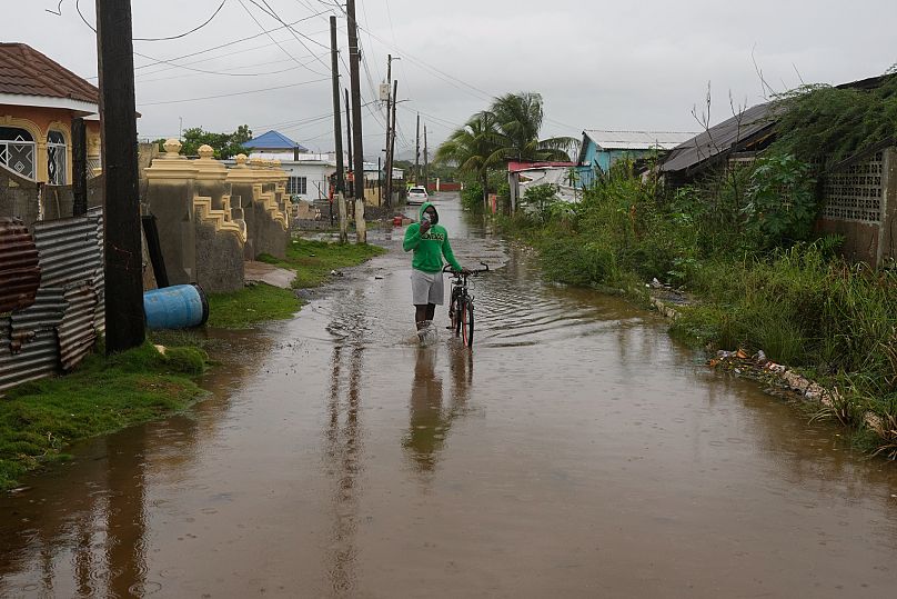 Um homem atravessa uma rua inundada antes da chegada prevista do furacão Melissa em Old Harbour, Jamaica, segunda-feira, 27 de outubro de 2025