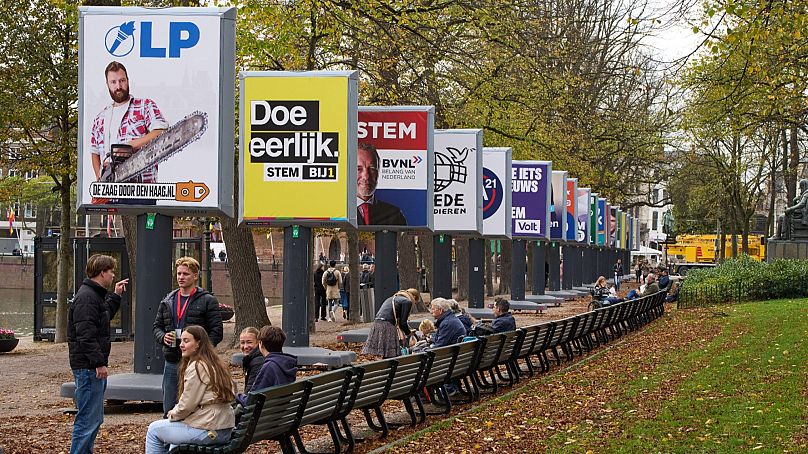 People enjoy the autumn weather next to some of the election billboards of 26 of the 27 political parties participating in the Oct. 29 general elections in The Hague.