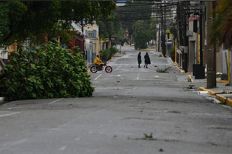 People walk in Kingston, Jamaica, as Hurricane Melissa makes landfall, Tuesday, Oct. 28