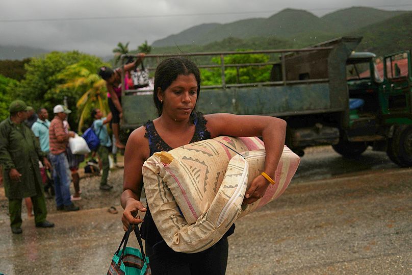 A woman carrying a mattress in the rain evacuates before the arrival of Hurricane Melissa in Cañizo, a community in Santiago de Cuba