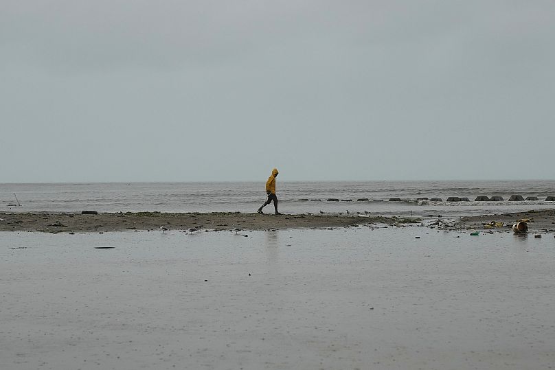 A man walks along the coastline ahead of the forecasted arrival of Hurricane Melissa in Old Harbour