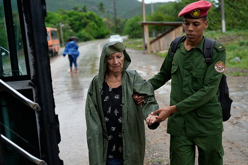 A soldier helps a woman evacuate before the arrival of Hurricane Melissa in Canizo, a community in Santiago de Cuba