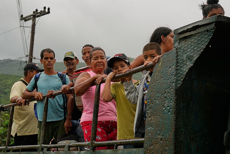 People ride in the back of a truck as they evacuate before the arrival of Hurricane Melissa in Canizo, a community in Santiago de Cuba, Tuesday, Oct. 28, 2025. (AP Photo/Ramón
