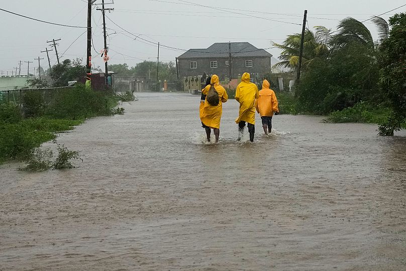 People walk along a road during the passing of Hurricane Melissa in Rocky Point, Jamaica, Tuesday, Oct. 28, 2025. (AP Photo/Matias Delacroix)